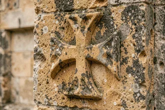 Croix des Templiers sculptée en relief sur une pierre calcaire ancienne, détail de la croix pattée médiévale